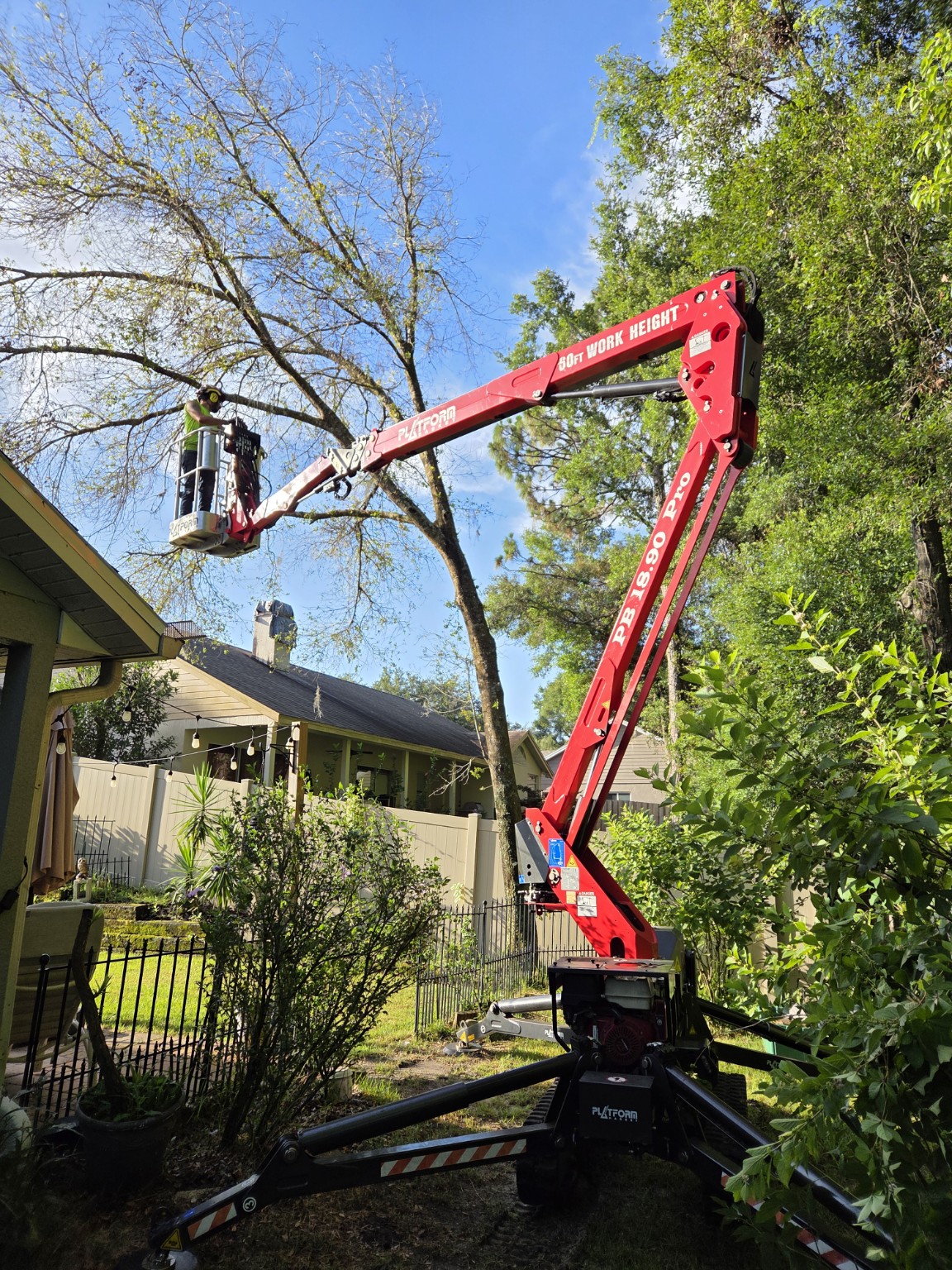 Compact red spider lift positioned between homes near fencing and landscaping