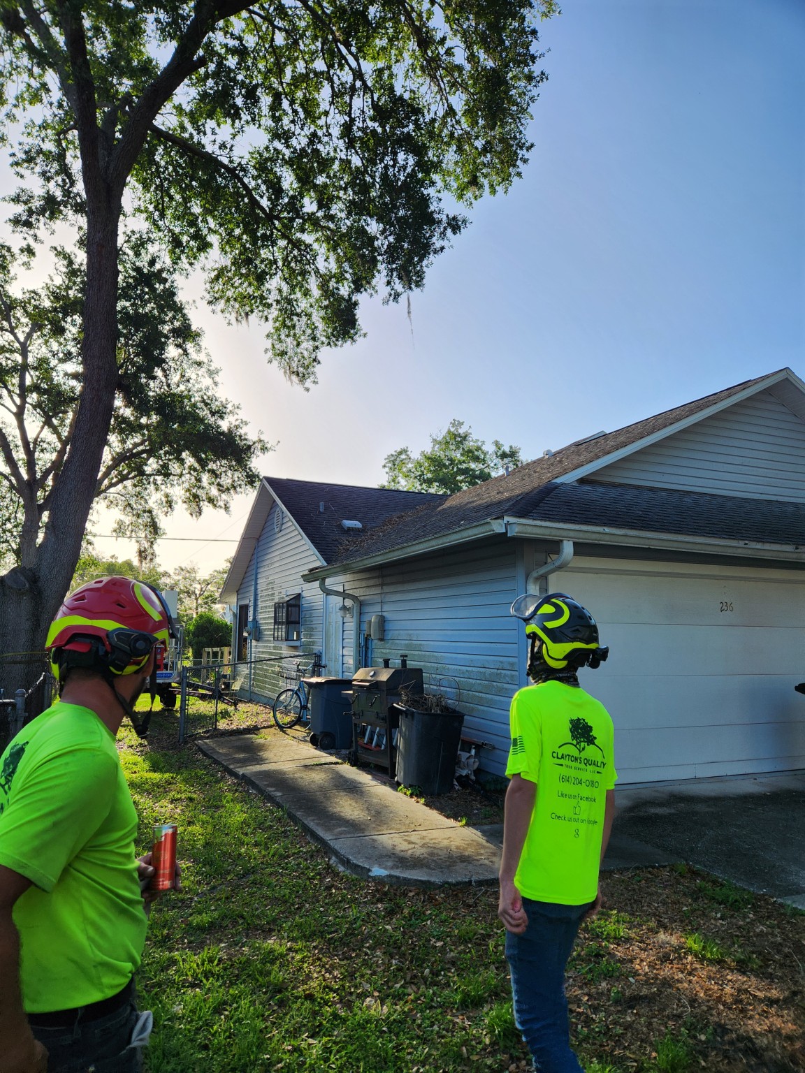 Clayton’s Quality crew wearing helmets beside a customer’s home